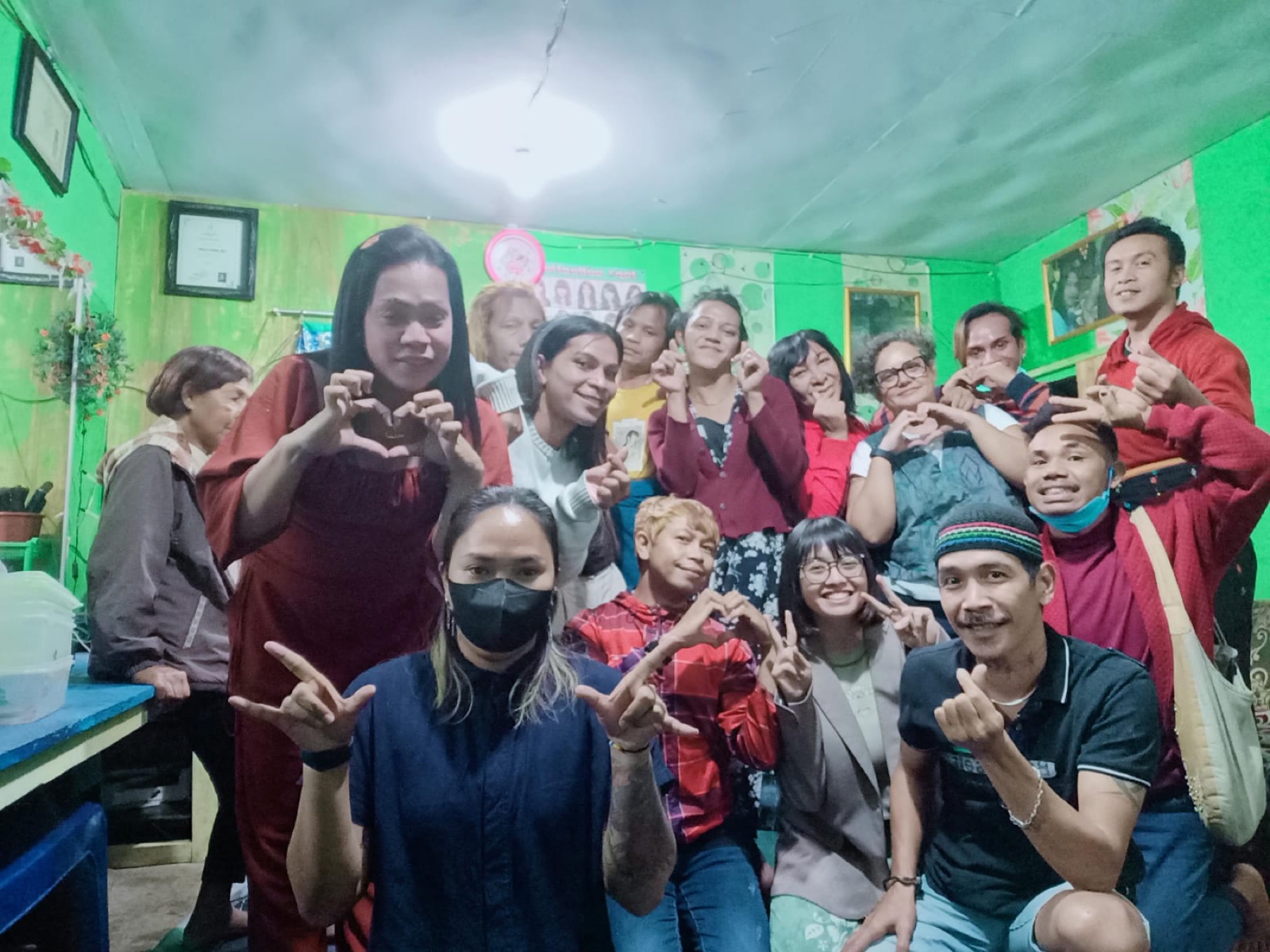 A community group gathered together making heart signs